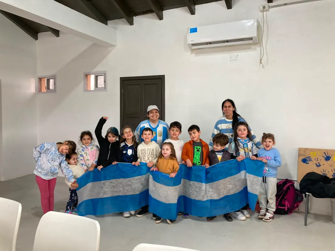 Foto grupal de chicos y adultas con una bandera argentina